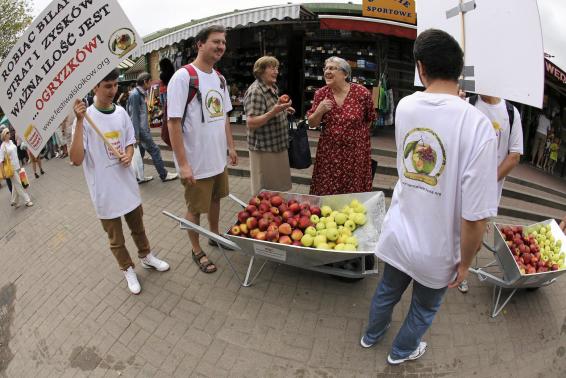 Young people march with a wheel barrow of apples during an event promoting Polish apples in Warsaw
