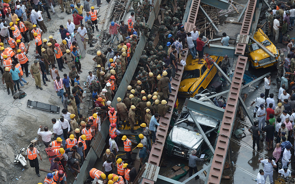 Indian rescue workers and volunteers try to free people trapped under the wreckage of a collapsed fly-over bridge in Kolkata on March 31, 2016. At least 14 people were killed and dozens more injured when a flyover collapsed in a busy Indian city on March 31, an official said, as emergency workers battled to rescue people trapped under the rubble.  / AFP / Dibyangshu SARKAR        (Photo credit should read DIBYANGSHU SARKAR/AFP/Getty Images)
