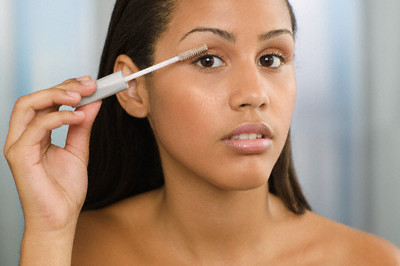 Young woman applying mascara