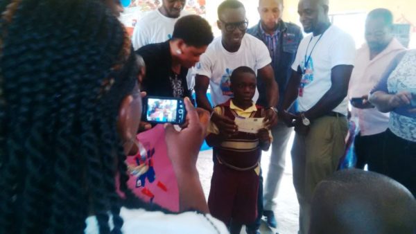 Ememobong Christopher Felix (middle) receiving his cheque of 70 thousand naira for winning the first position in the Imagine and Achieve Art Competition at the Archbishop International Nursery and Primary School, Uyo