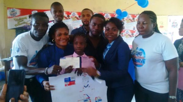 Goodness Vitalis Onwuegbulem (middle) displaying her cheque of 50 Thousand Naira for winning the second position in the Imagine and Achieve Art Competition from the Arcing Nursery and Primary School, Uyo