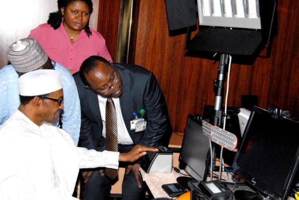 PIC.6. PRESIDENT MUHAMMADU BUHARI BEING CAPTURED FOR THE NATIONAL  IDENTITY MANAGEMENT COMMISSION'S (NIMC) IDENTITY CARD AT THE PRESIDENTIAL  VILLA IN ABUJA ON TUESDAY (25/8/15) WITH HIM IS THE DIRECTOR-GENERAL OF  NIMC, MR CHRIS ONYEMENEM. 6164/25/8/2015/ICE/CH/NAN