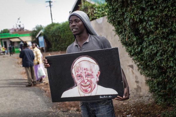 NAIROBI, KENYA - NOVEMBER 24: Artist Simon Kizito tries to sell his painting of Pope Francis in Nairobi's Kangemi slum on November 24, 2015 in Kenya. Pope Francis makes his first visit to Kenya on a five day African tour that is scheduled to include Uganda and the Central African Republic. Africa is recognised as being crucial to the future of the Catholic Church with the continentís Catholic numbers growing faster than anywhere else in the world. (Photo by Nichole Sobecki/Getty Images)