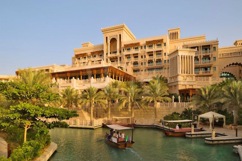Dubai. Al Qasr Hotel, built in the style of a Moroccan palace, seen over one of the Madinat Jumeirah’s canals with an abra, a water taxi.