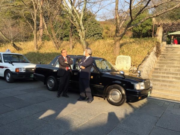 2 impeccably dressed taxi drivers waiting for passengers