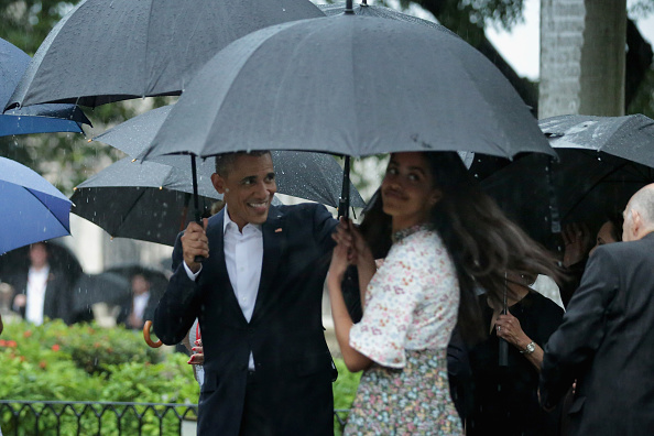 HAVANA, CUBA - MARCH 20: Taking shelter from the pouring rain under umbrellas, U.S. President Barack Obama, his daughter Malia, 17, and members of the first family take a walking tour of in the plaza of the 18th century Catedral de San Cristobal de la Habana in the historic Old Havana neighborhood March 20, 2016 in Havana, Cuba. Obama is the first sitting president to visit Cuba in nearly 90 years. (Photo by Chip Somodevilla/Getty Images)