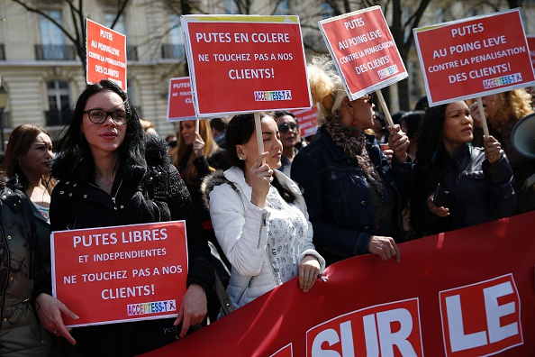 A protester (C) holds a sign reading "Angry prostitutes, don't touch our clients!" during a demonstration by sex workers and supporters near the French National Assembly in Paris on April 6, 2016, as French lawmakers take part in a final debate on a bill that would make it illegal to pay for sex. French lawmakers were poised on April 6 to pass a controversial law that makes it illegal to pay for sex and imposes fines of up to 3,500 euros ($3,970) on prostitutes' clients. / AFP / THOMAS SAMSON (Photo credit should read THOMAS SAMSON/AFP/Getty Images)