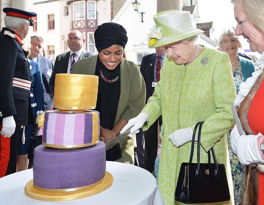 WINDSOR, ENGLAND - APRIL 21: Queen Elizabeth II receives a birthday cake from Nadiya Hussain, winner of the Great British Bake Off, during her 90th Birthday Walkabout on April 21, 2016 in Windsor, England. Today is Queen Elizabeth II's 90th Birthday. The Queen and Duke of Edinburgh will be carrying out engagements in Windsor. (Photo by John Stillwell - WPA Pool/Getty Images)