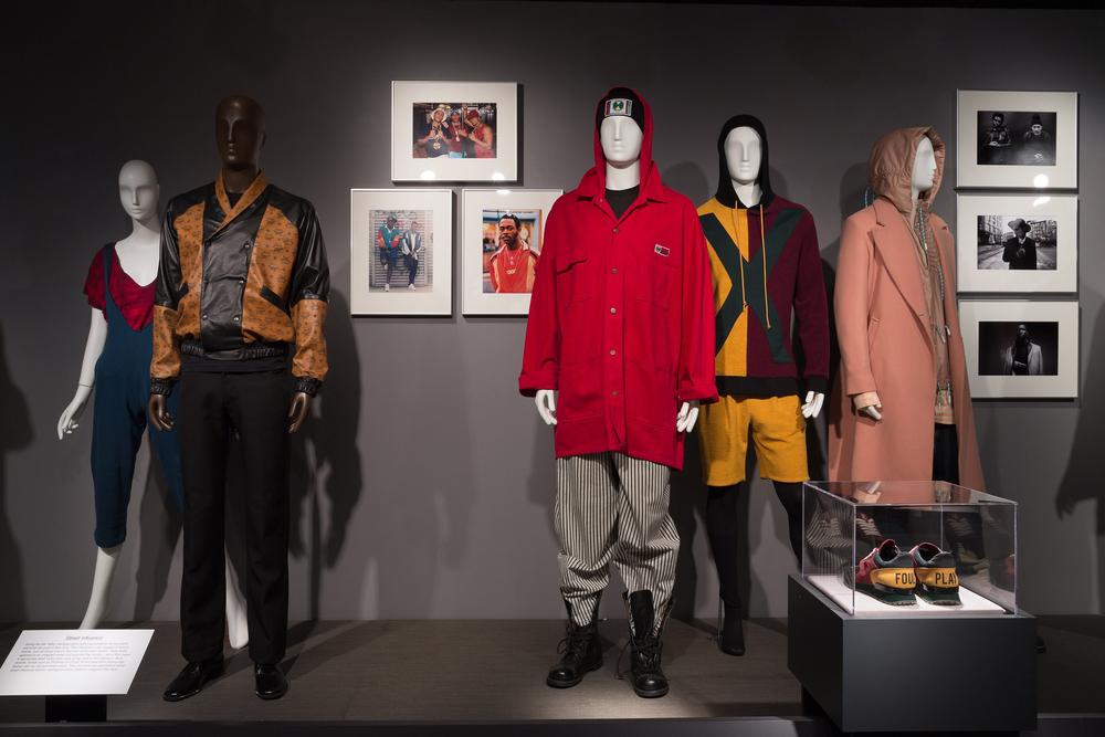 Photo credits (from left to right): Isaïa, ensemble, 1980, USA. Gift of Ms. Terry Melville. Dapper Dan of Harlem, jacket, 1987, USA. Gift of Dapper Dan of Harlem. Photographs by Jamel Shabazz, late-1980s. Cross Colours, ensemble, 1990-1993, USA. Gift of Michael Harrell. Photographs by Dario Calmese 2012-2014. Off-White, ensemble, fall 2015, USA. Gift of Off-White c/o Virgil Abloh. Pyer Moss, ensemble and shoes (in case), fall 2015, USA. Gift of Pyer Moss.