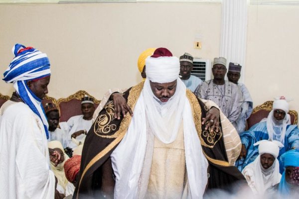 The Dan Amana being decorated with ceremonial robe by some palace assistants.