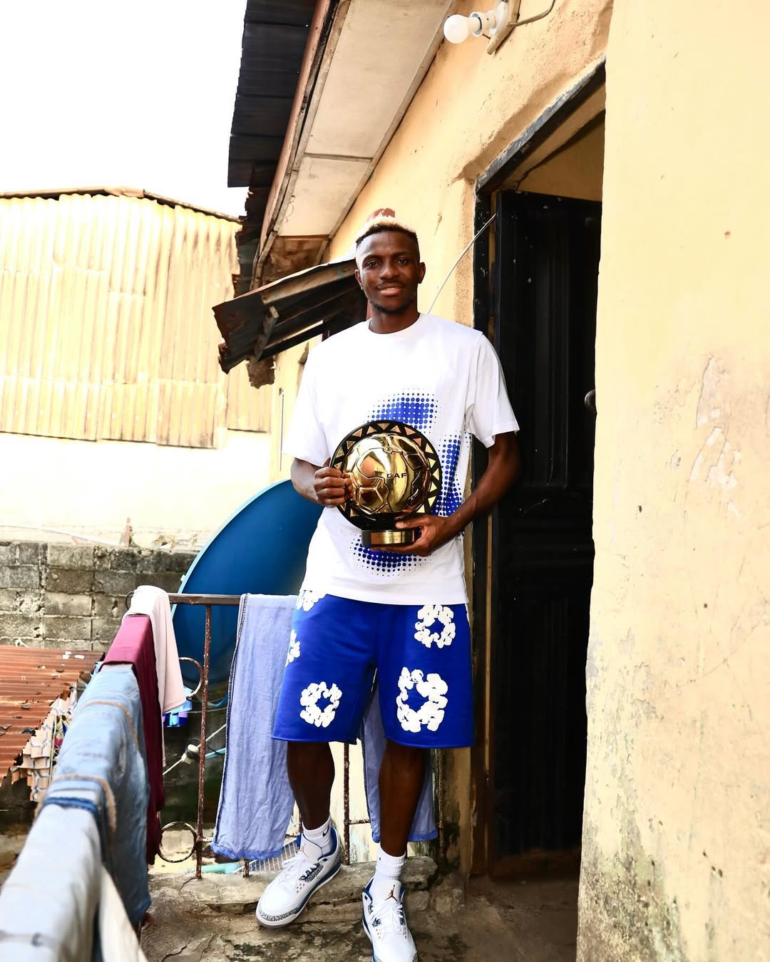 Victor Osimhen holds his CAF trophy at his childhood home in Olusosun, Lagos.