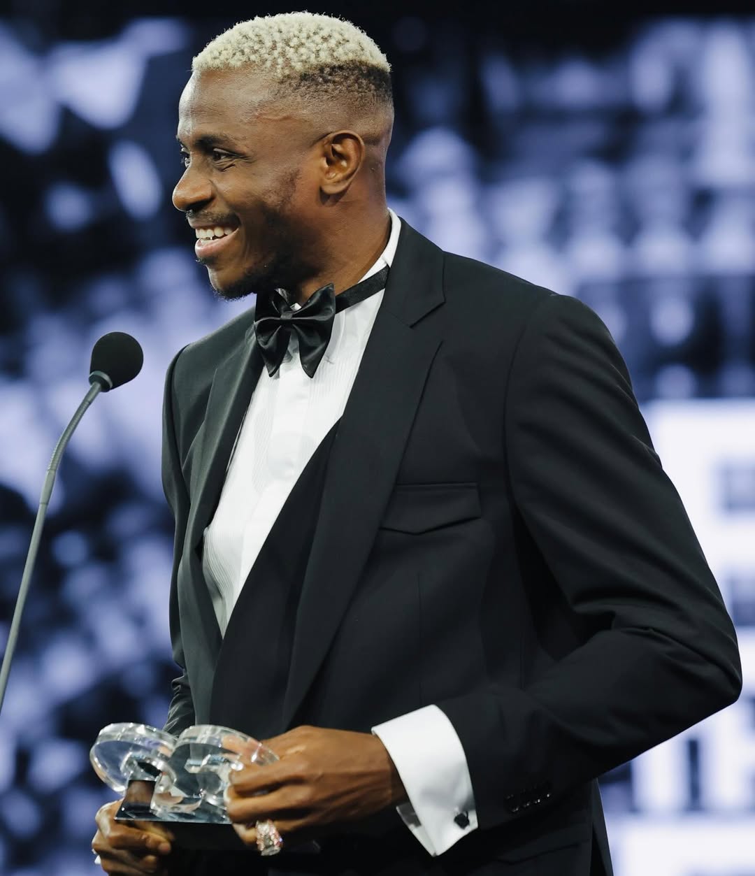 Victor Osimhen smiles in a black tuxedo after winning Sportsman of the Year at the 2025 GQ Türkiye Men of the Year Awards.