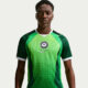 A male model wearing the 2026 Nike Super Eagles home jersey in a vibrant lemon green with dark green armour-style side panels.