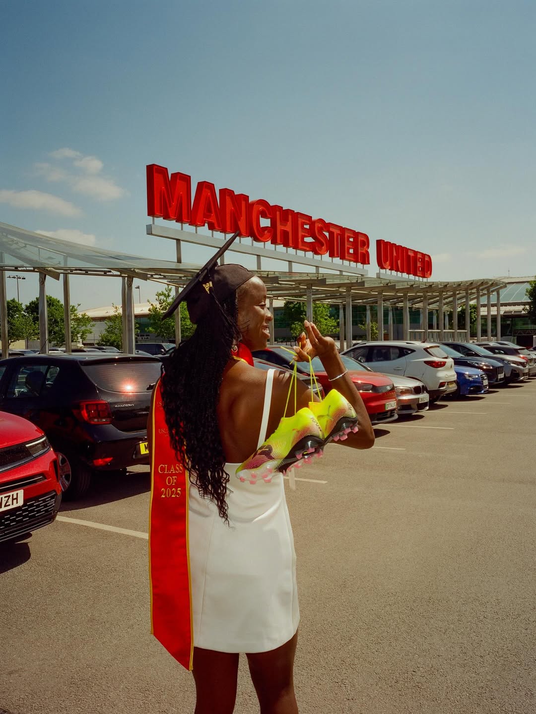 Simi Awujo in a black graduation cap and gown, holding her University of Southern California (USC) diploma cover, smiling against a backdrop of red and yellow USC commencement banners as she celebrates her dual degree in Computer Science and Business Administration.