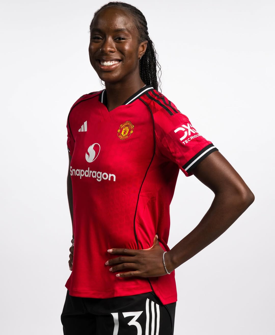 Official studio portrait of Simi Awujo, Manchester United Women’s midfielder. She is smiling, with her hair in neat braids, wearing the 2025/26 red home kit featuring the Snapdragon sponsor logo.