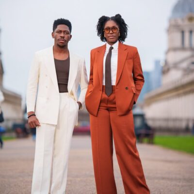 Moses Bliss in a cream double-breasted suit and Marie Bliss in a rust-colored oversized suit for their 2nd wedding anniversary photoshoot in London.