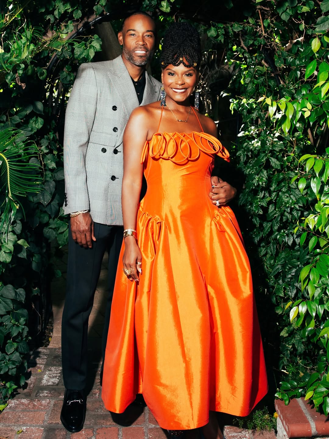 Actress Tabitha Brown, in a vivid orange gown by Nigerian designer Desirée Iyama, and her husband Chance Brown at the 2026 NAACP Image Awards in Pasadena.