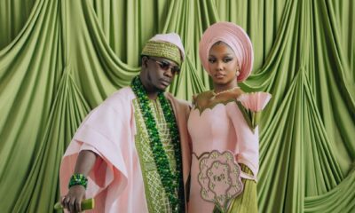 Simi Sanya and Femi Dapson posing for their first look at their traditional wedding in blush pink and forest green outfits.
