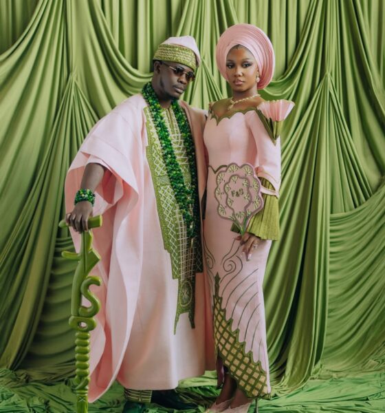 Simi Sanya and Femi Dapson posing for their first look at their traditional wedding in blush pink and forest green outfits.