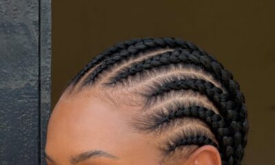 A profile close-up of Temiloluwa Ajibade in Accra, showing her neat, back-braided cornrows, gold ribbed stud earrings, and a blue dalmatian-print collar.