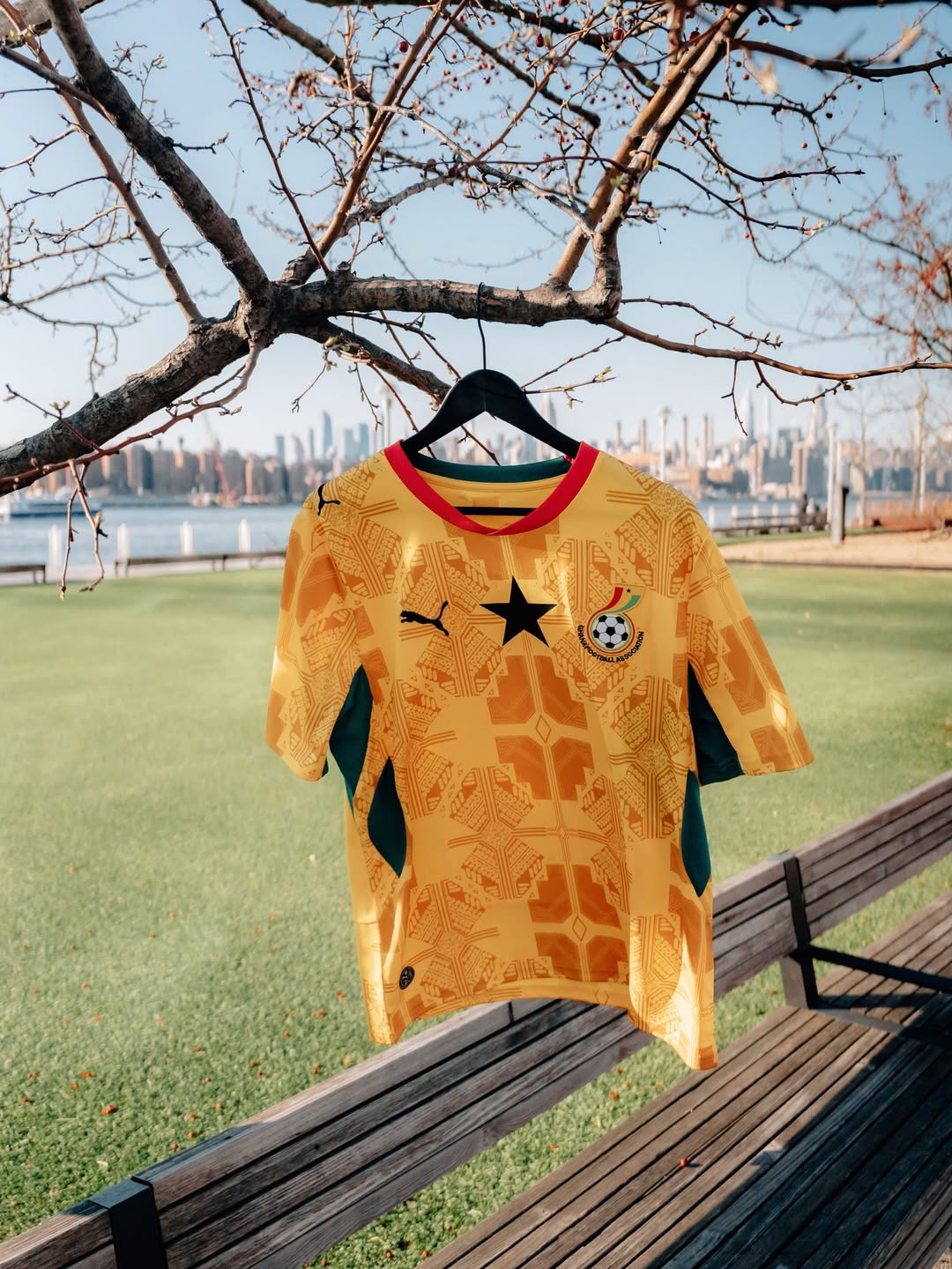 A detailed shot of the 2026 Puma Ghana away jersey in sunny yellow, featuring tonal Adinkra symbols and a red collar.