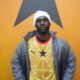 Ghanaian musician Black Sherif wearing the 2026 yellow Ghana away jersey with a grey jacket and white beanie.