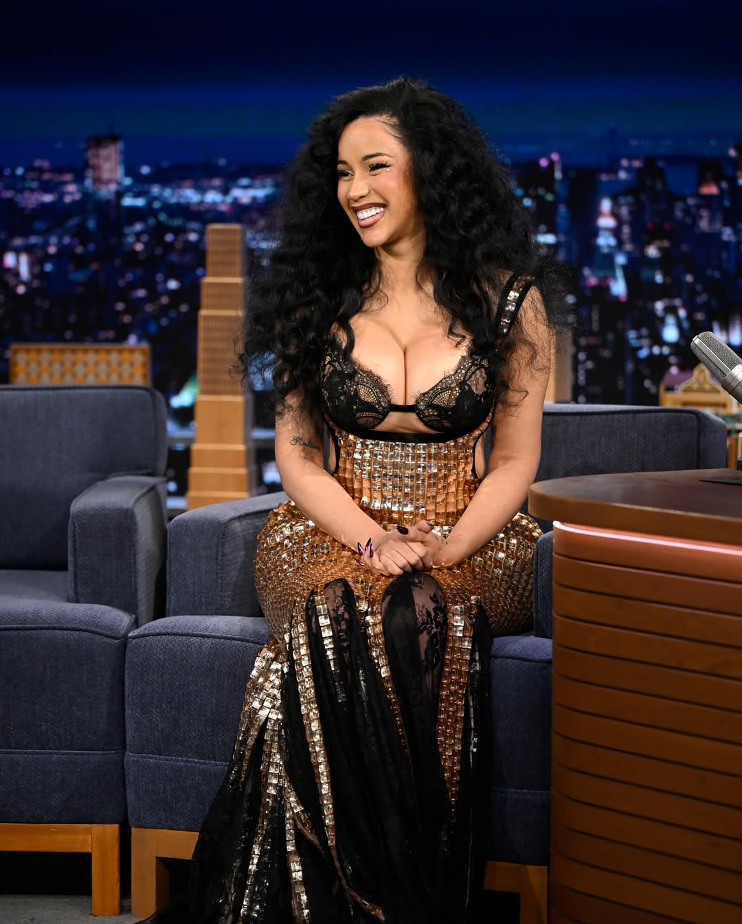 Cardi B sitting with Jimmy Fallon on The Tonight Show stage during her March 2026 appearance.