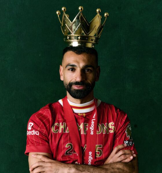 A close-up studio portrait of Mohamed Salah in the Liverpool home kit, capturing his focused "Egyptian King" expression.