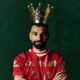 A close-up studio portrait of Mohamed Salah in the Liverpool home kit, capturing his focused "Egyptian King" expression.