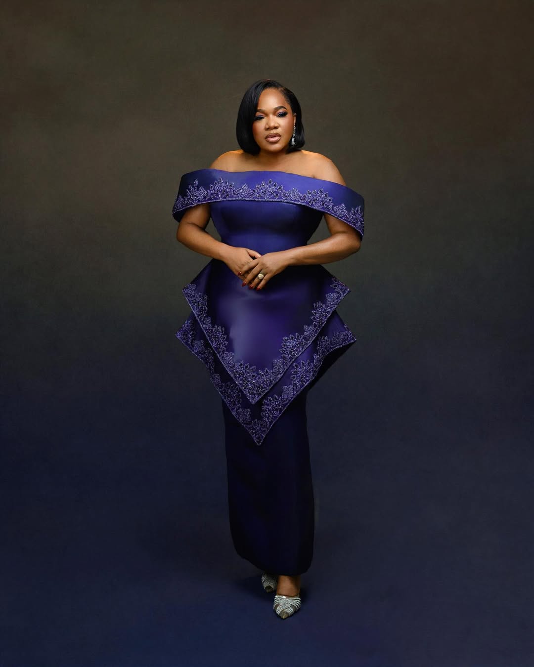 Toyin Abraham in a deep navy blue off-shoulder gown by Prudential with an asymmetric peplum panel for The Return of Arinzo premiere.