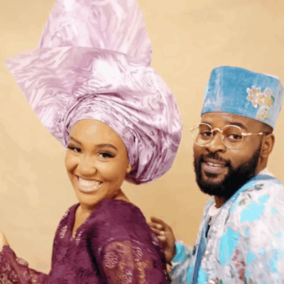 Falz in a turquoise floral Agbada and a model in a purple lace buba and lilac Gele posing together.