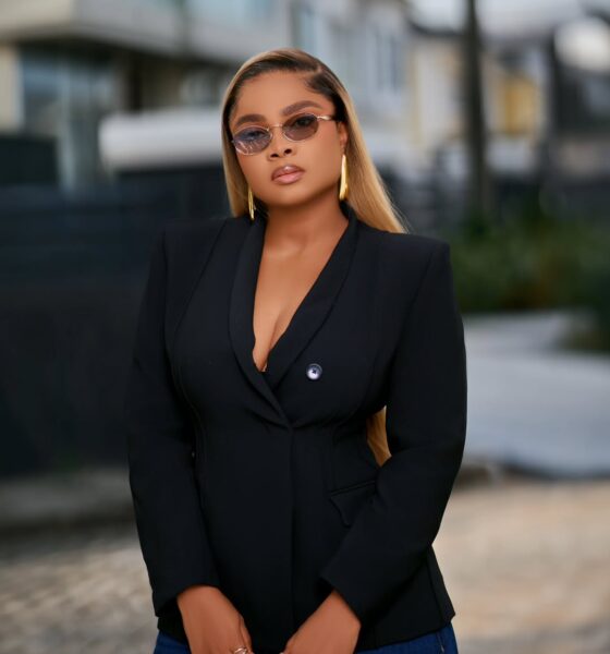 Bimbo Ademoye wearing a black blazer and tinted sunglasses in a professional outdoor portrait.