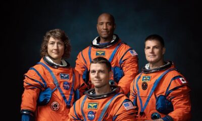 Official portrait of Artemis II astronauts Christina Koch, Victor Glover, Reid Wiseman, and Jeremy Hansen in orange flight suits.
