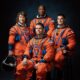 Official portrait of Artemis II astronauts Christina Koch, Victor Glover, Reid Wiseman, and Jeremy Hansen in orange flight suits.