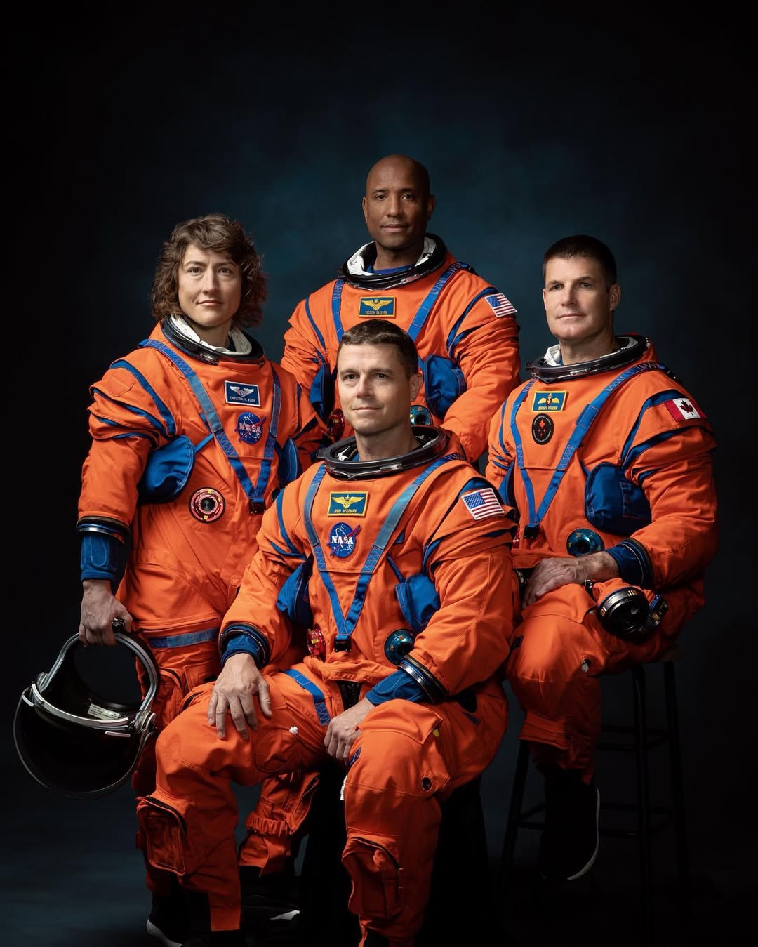 Official portrait of Artemis II astronauts Christina Koch, Victor Glover, Reid Wiseman, and Jeremy Hansen in orange flight suits.