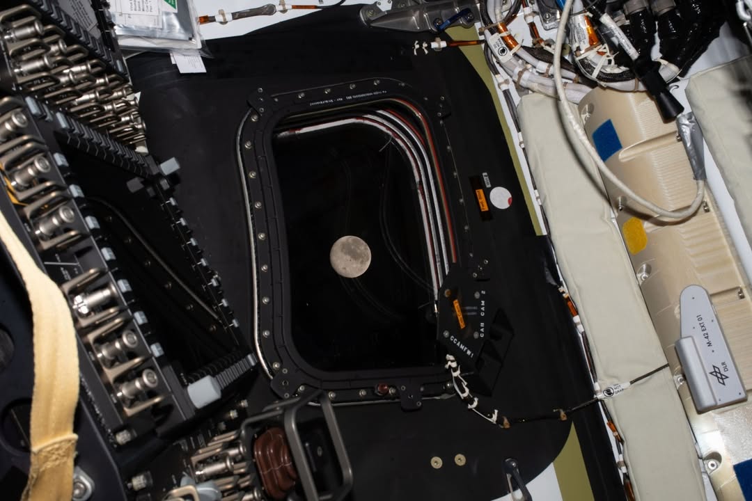 The Moon seen through a small circular porthole from the interior of the Orion spacecraft cabin
