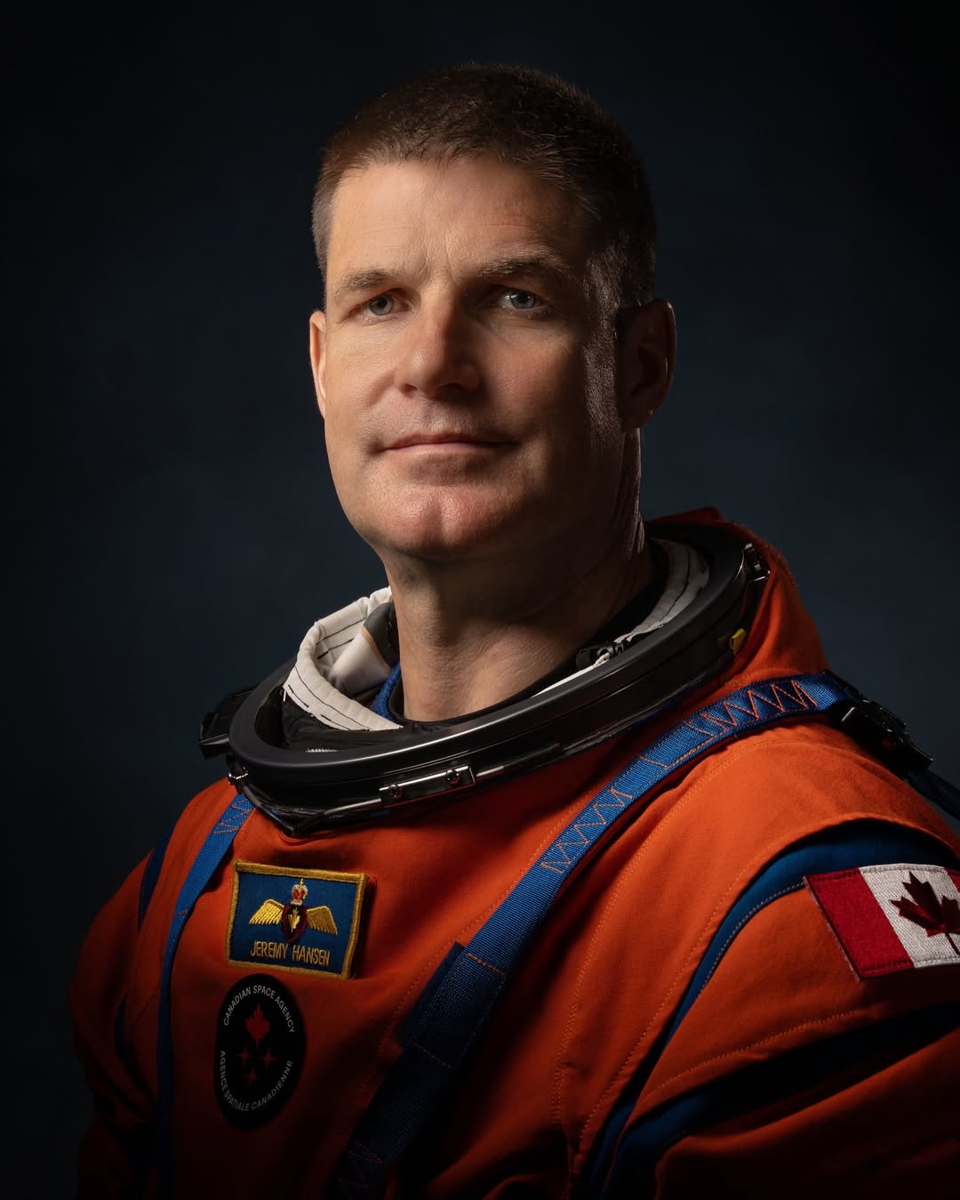 Canadian Space Agency astronaut Jeremy Hansen in an orange Artemis flight suit with a Canadian flag patch.