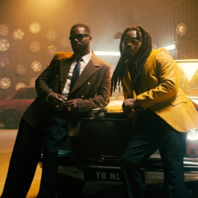 Adekunle Gold and Olamide posing in a retro garage with a vintage Mercedes-Benz for their 2026 collaboration 'Formation.'