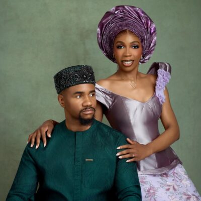 Nollywood actor Jide Kene Achufusi in a forest green Agbada and black beaded cap seated beside his bride, Ifeoma, who is wearing a lilac structured corset top and floral lace mermaid skirt for their pre-wedding photoshoot.