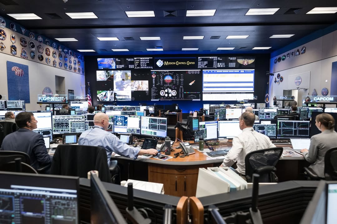 A view inside NASA’s Mission Control Center in Houston during the Artemis II re-entry, showing flight controllers at desks with multiple data screens.