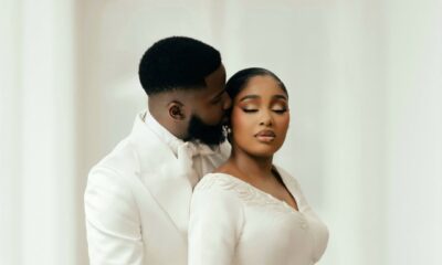 An intimate portrait of Akin Faminu embracing Kiky Festus from behind. Akin wears a white Deji and Kola dinner jacket; Kiky wears a bespoke ivory Mazelle Bridal two-piece set.