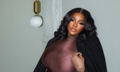 Dorathy Bachor wearing a chocolate brown mock-neck mini dress and a black blazer caped over her shoulders, holding a quilted leather clutch.