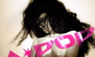 A grainy, high-contrast black-and-white portrait of Tyla with voluminous hair covering her face, overlaid with a bold pink "A*POP" graphic.