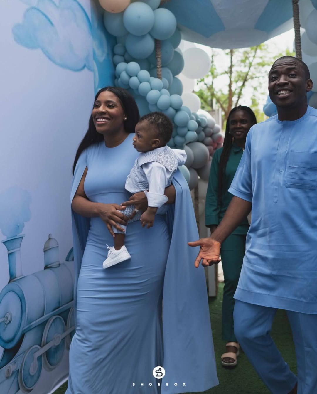 Theophilus Sunday and Ashlee Sunday wearing baby blue outfits while walking into their son Mystery's first birthday party.