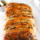 A golden-brown, freshly baked loaf of Kikifoodies' sardine pull-apart bread brushed with glossy, spicy oil and topped with chopped parsley and red pepper flakes.