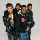 A tight group studio portrait of Nollywood stars Mike Afolarin, Chimezie Imo, Emeka Nwagbaraocha, and Tomiwa Tegbe looking directly into the camera in coordinated black jackets and streetwear.