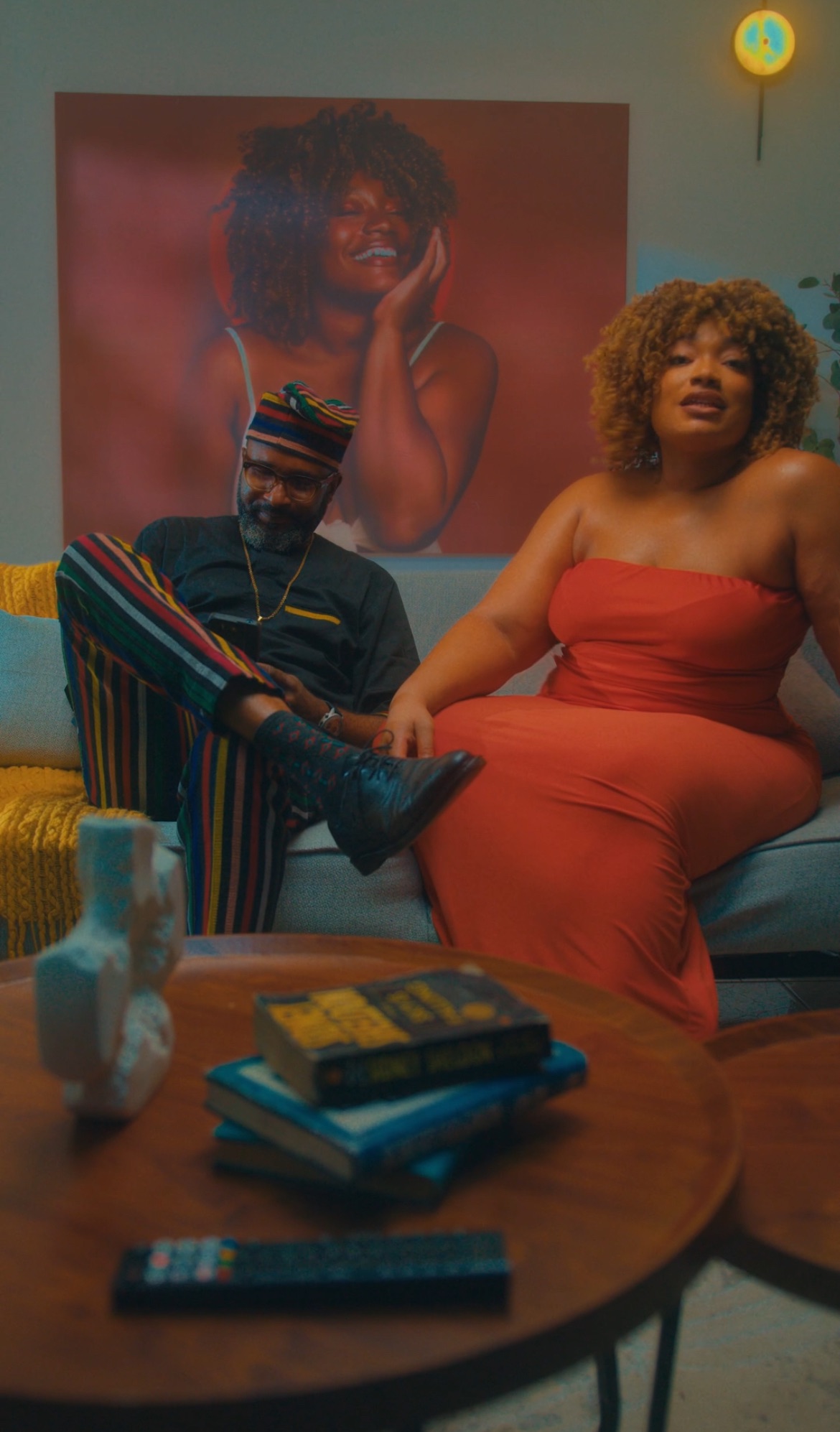 A cinematic still from Thick & Uninterrupted directed by Dominic Aikabeli showing characters Maya and a male lead in a moody, low-lit restaurant setting.