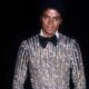 An archival photo of Michael Jackson wearing a black and silver sequined suit with a bow tie, representing his peak era as a global digital artist.