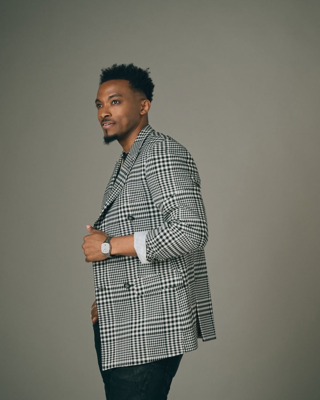 American gospel singer Jonathan McReynolds posing in a black and white houndstooth double-breasted blazer for his appearance on The Jennifer Hudson Show.