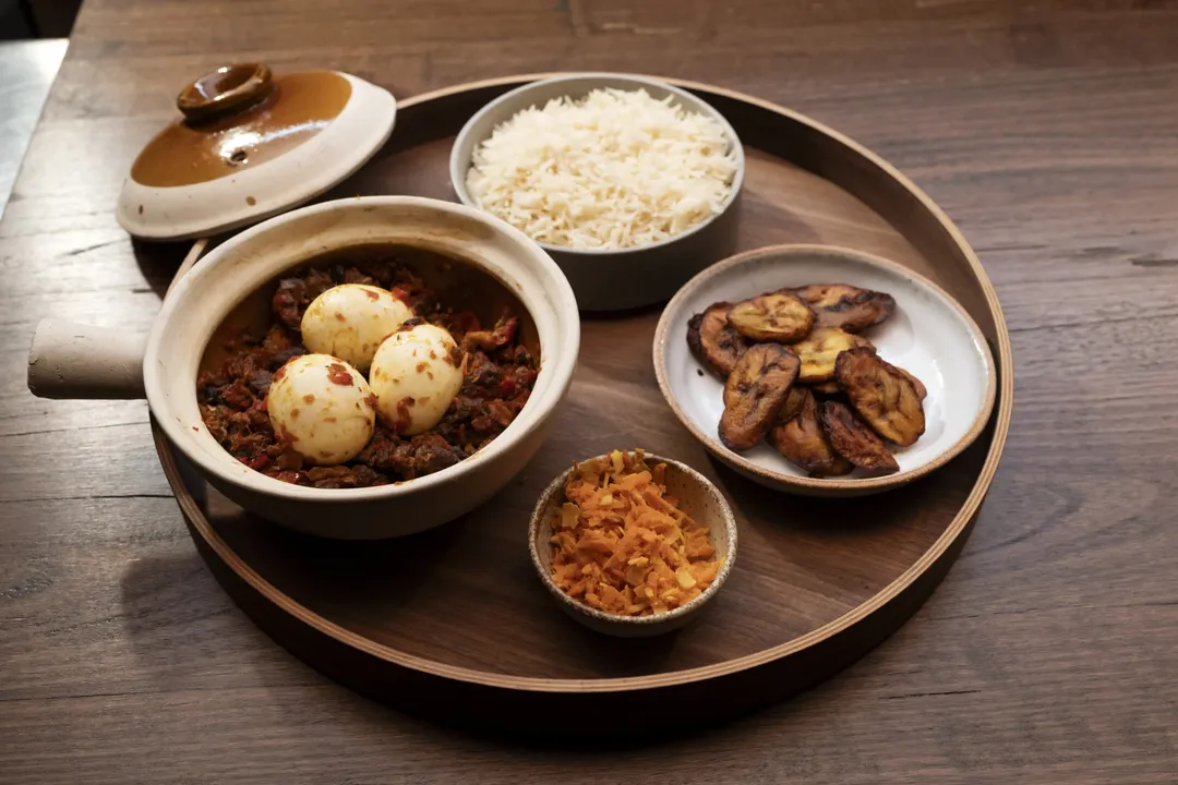 A traditional Nigerian Ofada stew with boiled eggs, served with rice, plantain, and a coconut and carrot sambal on MasterChef Australia 2026.